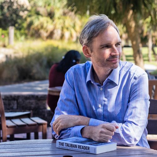 Professor sits with book title "Taliban Reader"