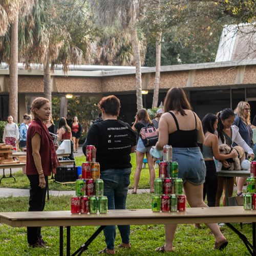 Students at tables outside with aluminum cans