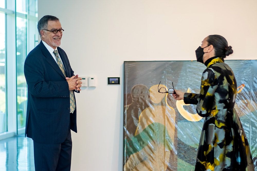 President smiles with colleague, large piece of artwork behind him