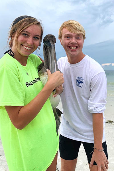 Two students with pelican on the beach