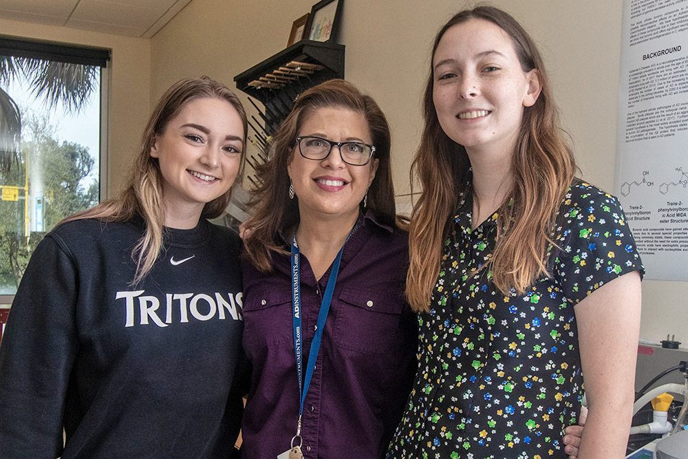 Professor stands in lab with a student on either side