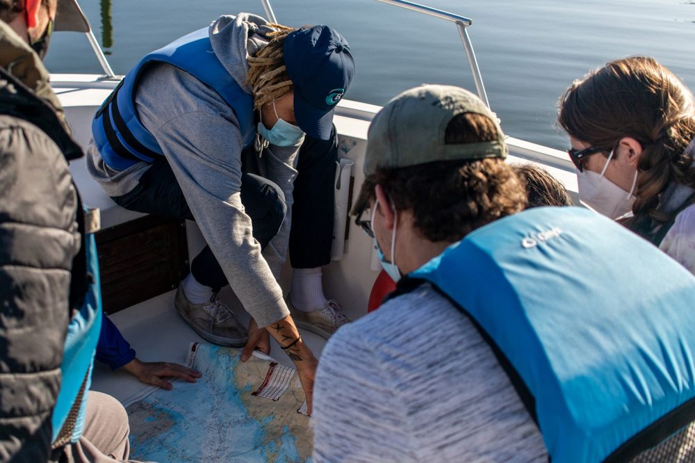 Students on small boat, looking at a large map