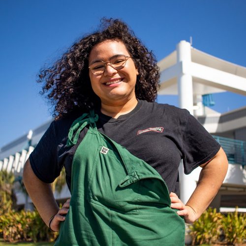 Student smiling with hands on hips in front of marine science laboratory