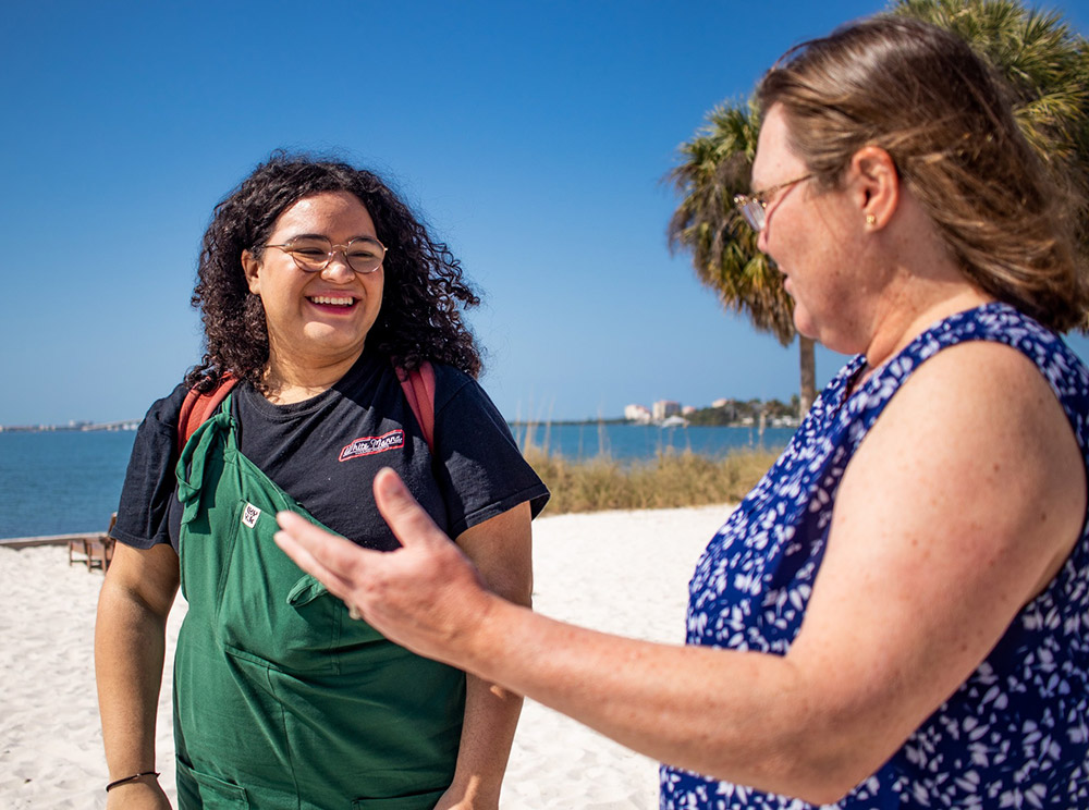 Student walking on the beach alongside professor