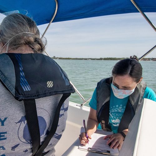 Professor on a boat, recording data on a notebook