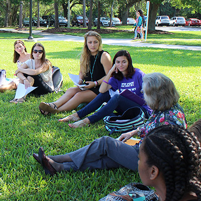 Professor seated in grass near students