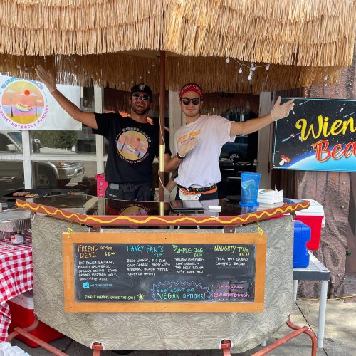 Two people welcoming folks to their popup tiki-style store