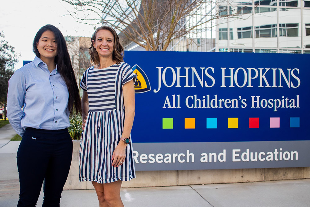 Professor and student in front of sign that reads Johns Hopkins All Children's Hospital