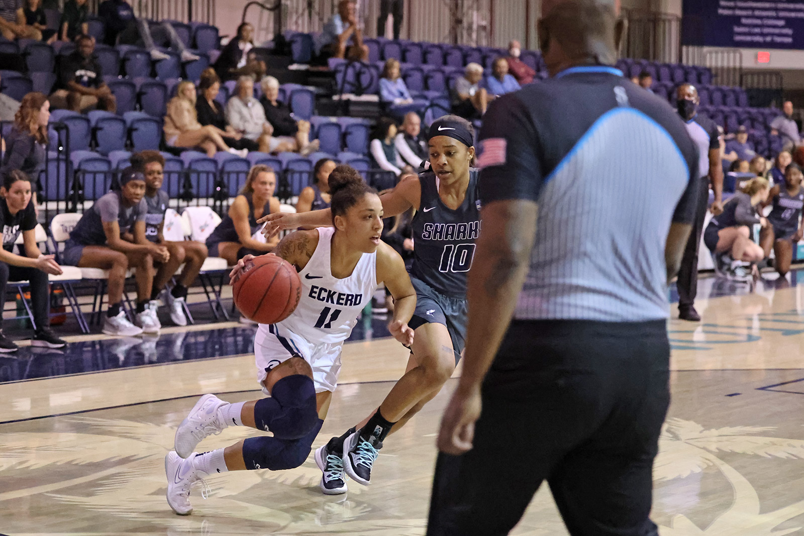 Women's basketball player dribbling ball around defender