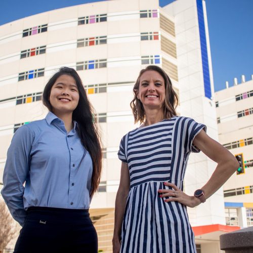 Professor and student stand before hospital building