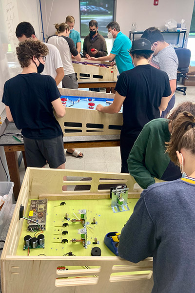Students and faculty working on three pinball machines