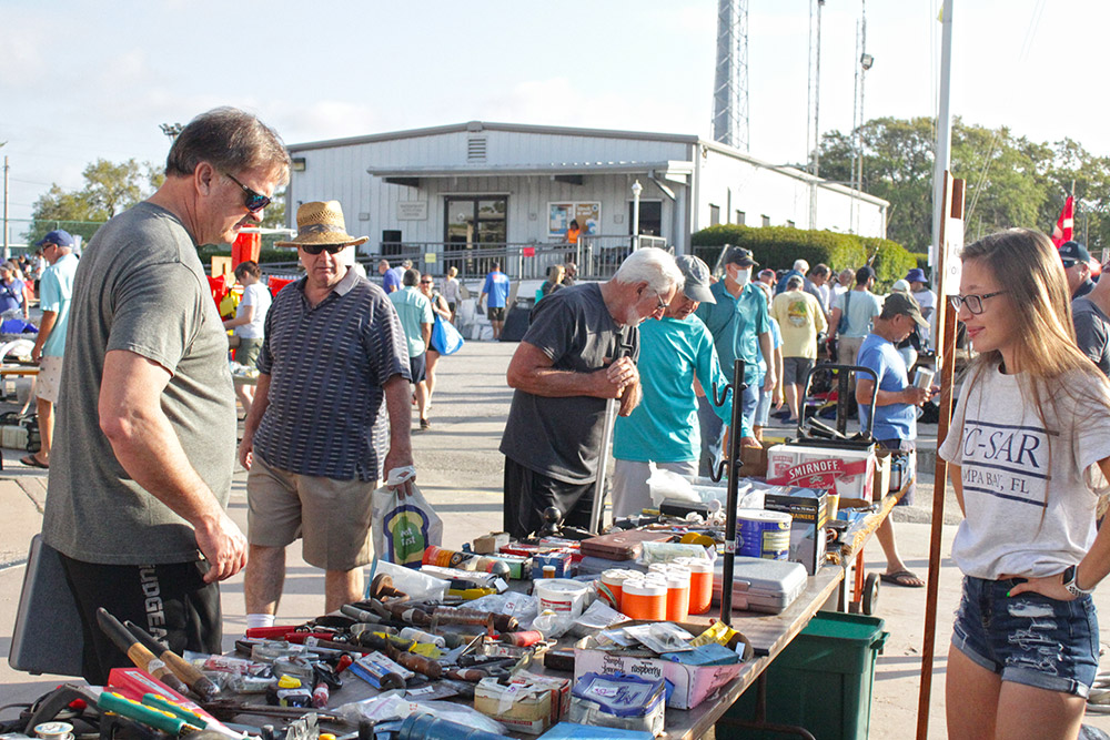 The public looks through yard sale materials as a student looks on to assist
