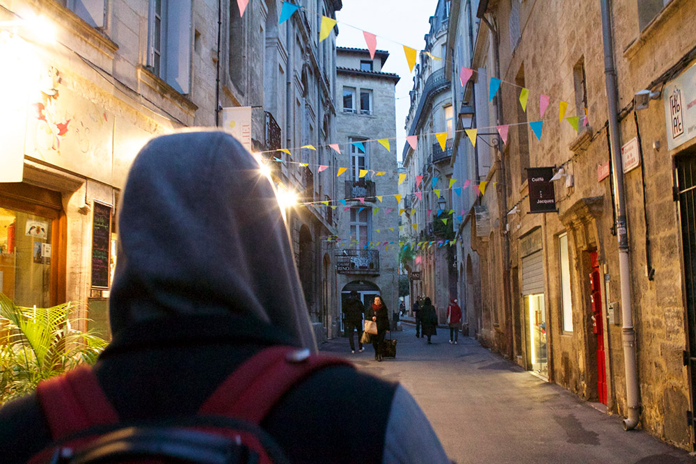 Student walking down a narrow street in France