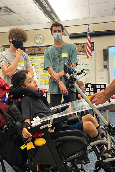 Eckerd students stand beside pupil in wheelchair