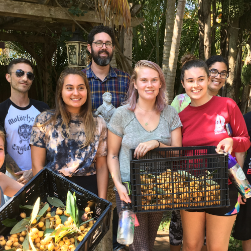 Professor standing with group of students holding boxes of loquats