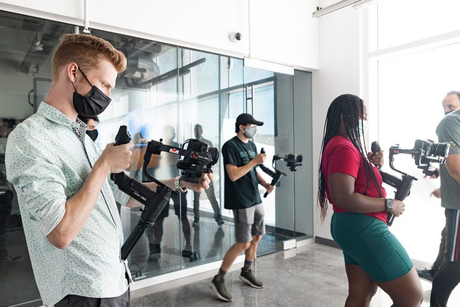 Students walking down hallway with camera equipment