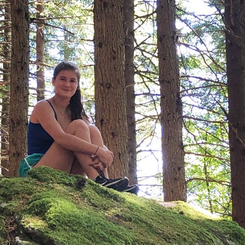 Student sitting on a rock in the woods