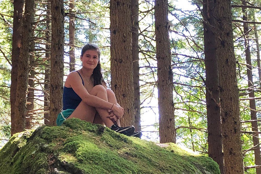 Student sitting on a rock in the woods