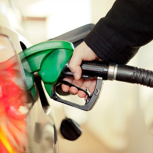 A hand pumps gas into a car's fuel tank.