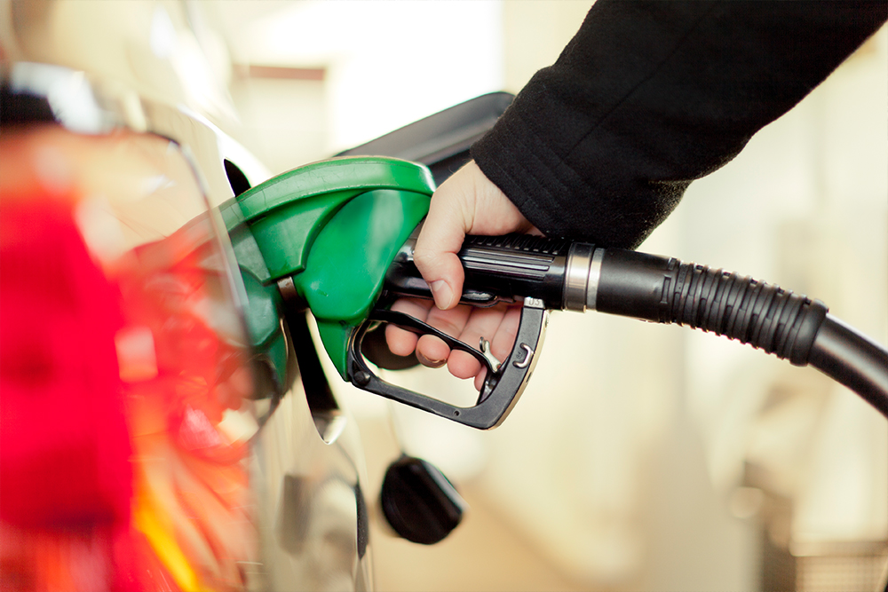 A hand pumps gas into a car's fuel tank.