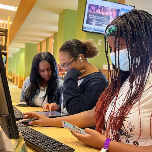 Three high school students in front of a computer