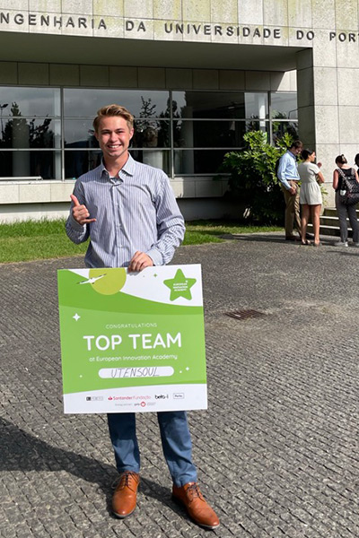 Student holding sign that reads "Top Team" while standing on campus in Porto
