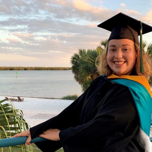 student in grad cap on balcony looking over the bay