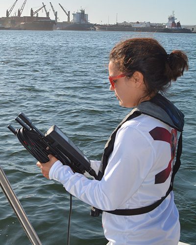 Student holding equipment while on a boat