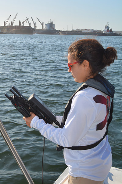 Student holding equipment while on a boat
