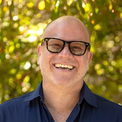 Professor wearing glasses, smiling at camera