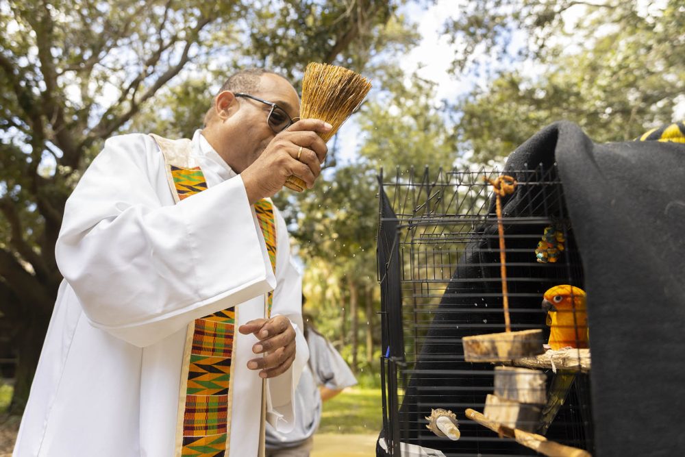 Father Stephan blesses a bird in cage