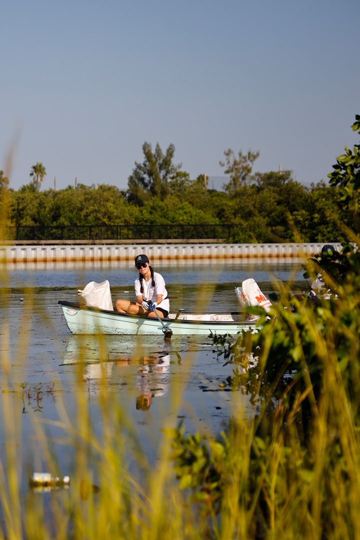 Student in a canoe pulling trash from the water