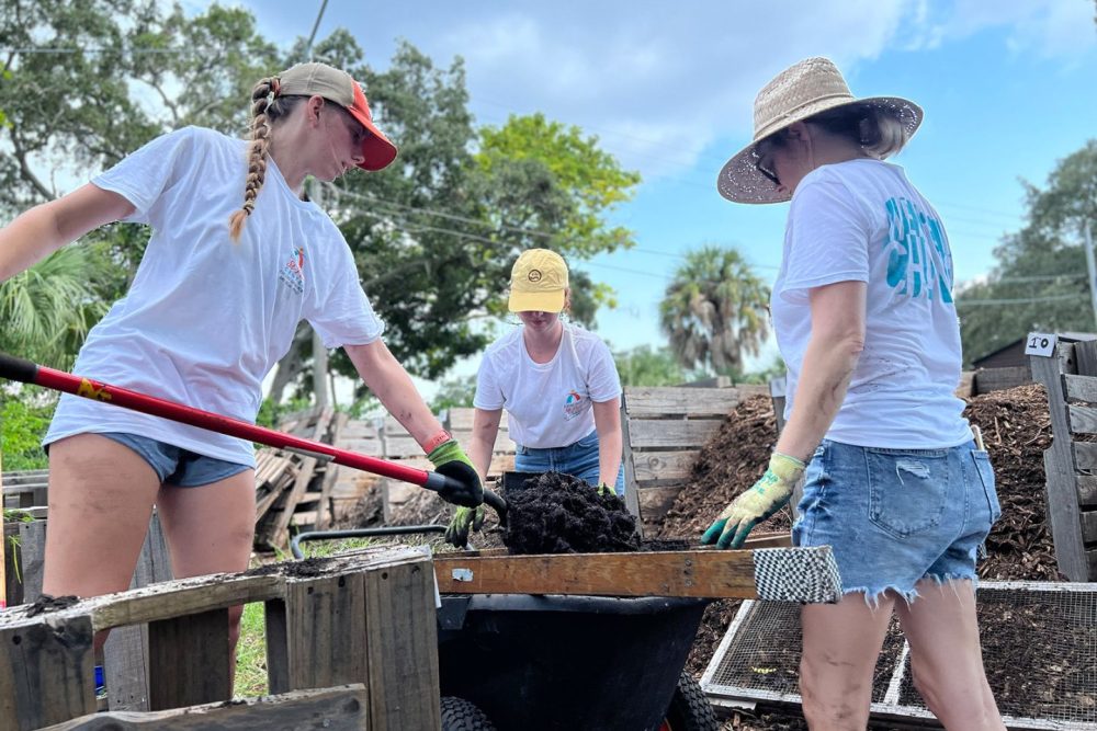 Student, staff person and alumna work sift through mulch