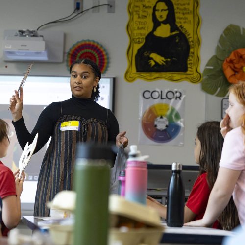 Eckerd student standing in front of class of school children