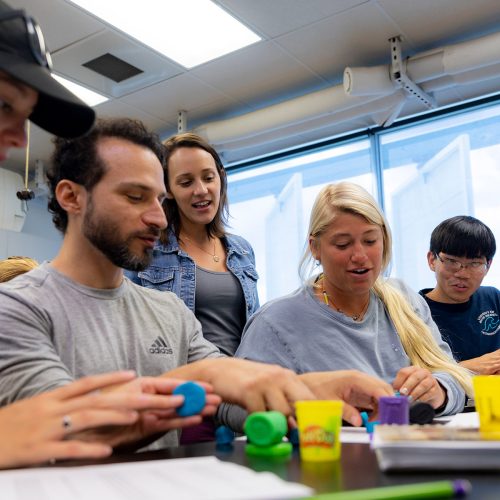 Professor watches over students working at a table together