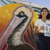 Student holding flowchart in front of mural of pelican