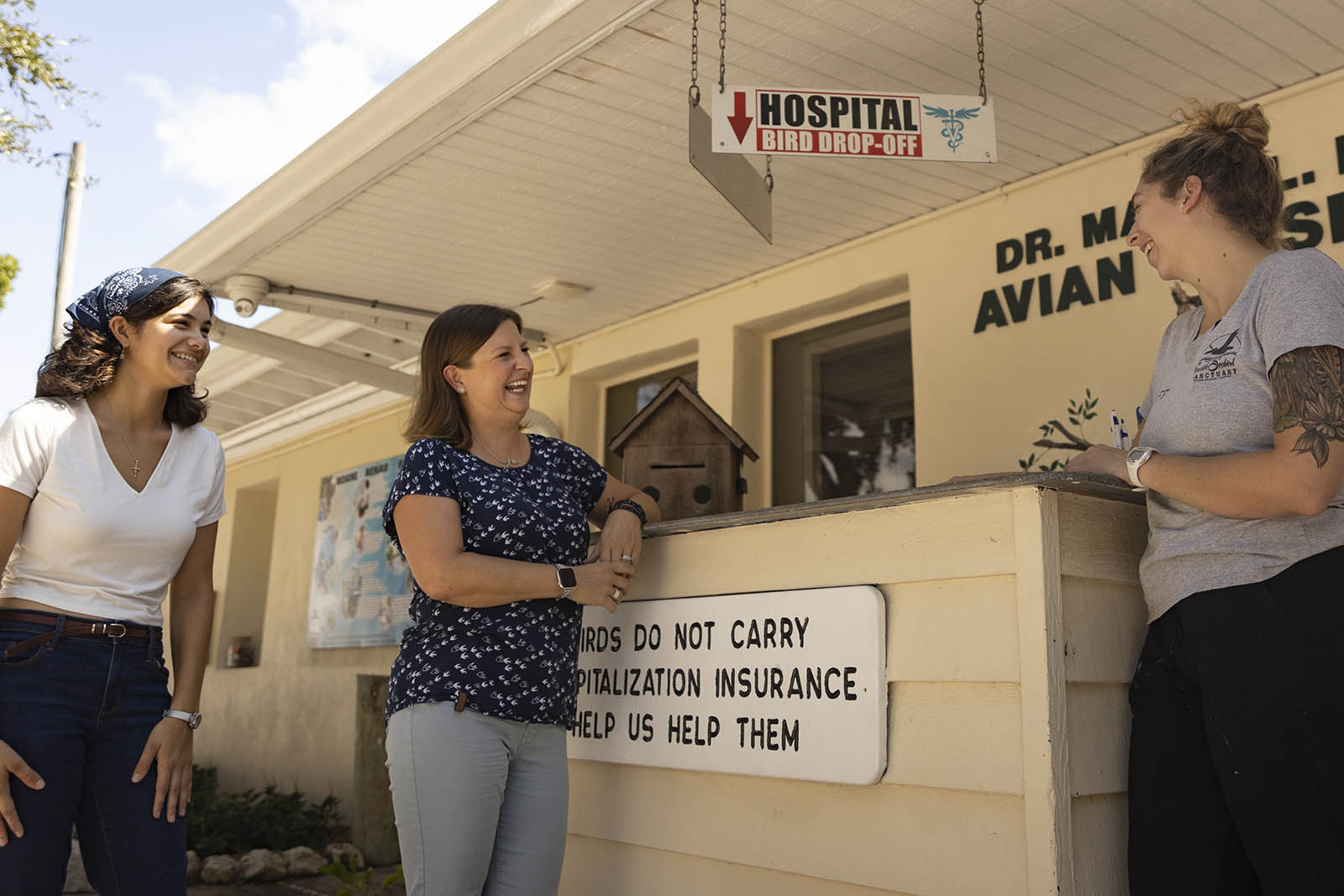 Student and professor chat with staff member in front of animal hospital sign