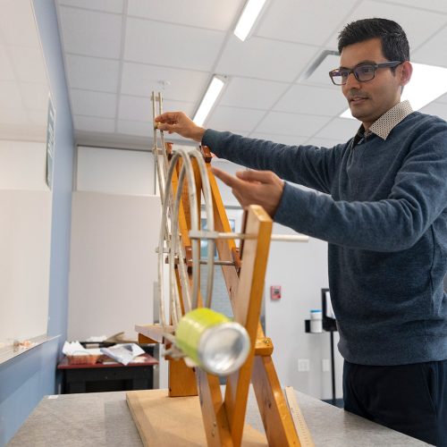 Physics professor in classroom pointing to equipment