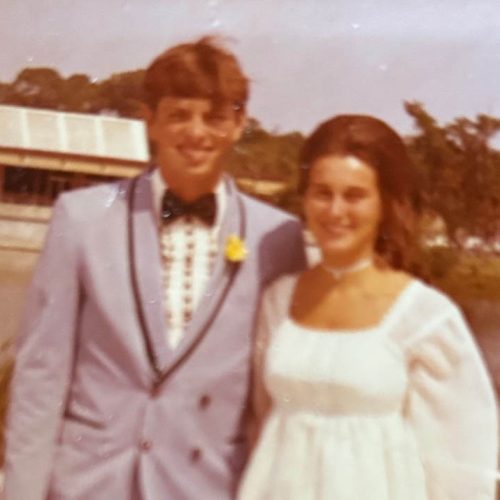 A couple standing in formal attire in front of pond