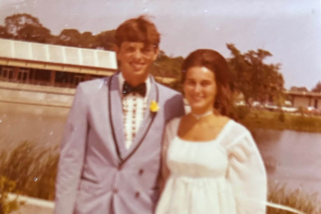 A couple standing in formal attire in front of pond