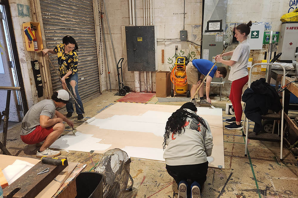 Students paint a big board inside a shop