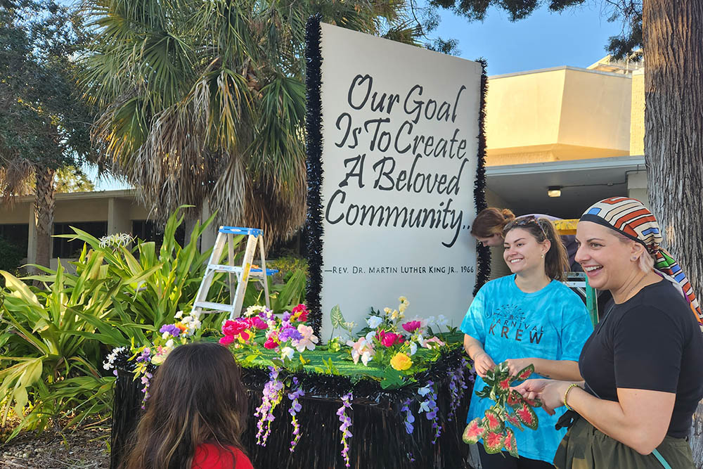 Students and staff stand next to the completed float on campus