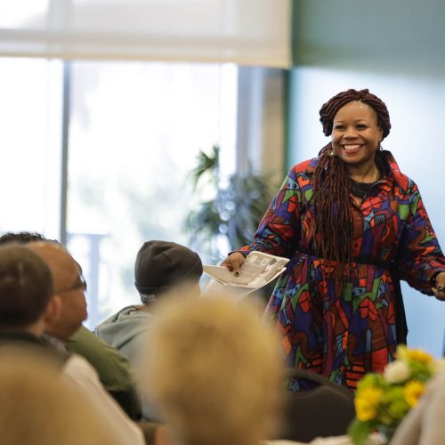 Woman holding microphone smiles at an audience