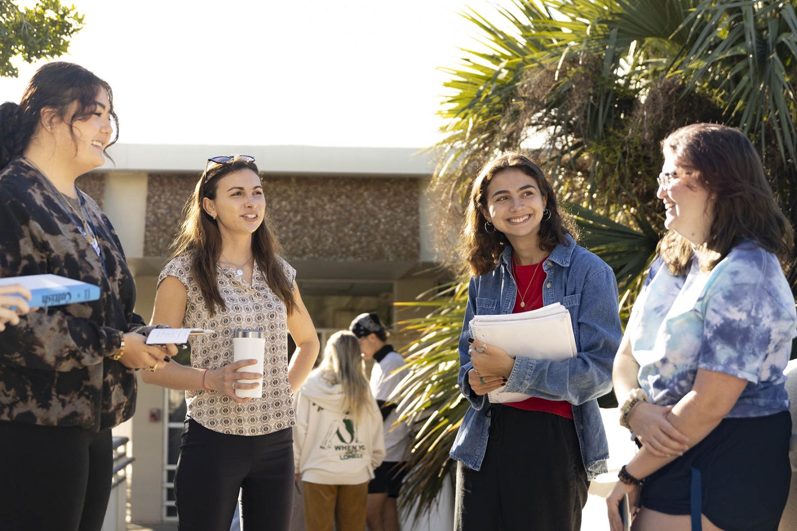 Professor stands with students outside chatting