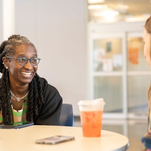 Woman speaks with a student at table