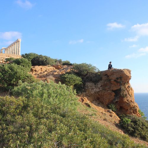 Student on a cliff near ancient ruin