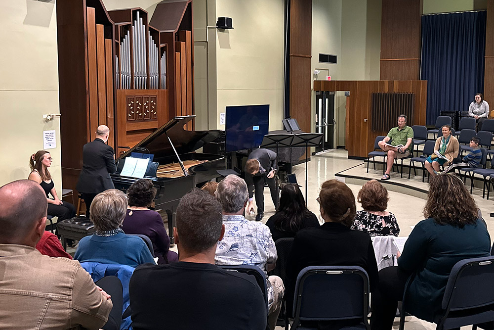 A seated audience faces pianist in a concert hall