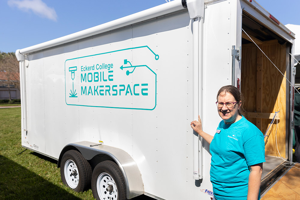 Professor standing in front a trailer that says "Mobile Makerspace"