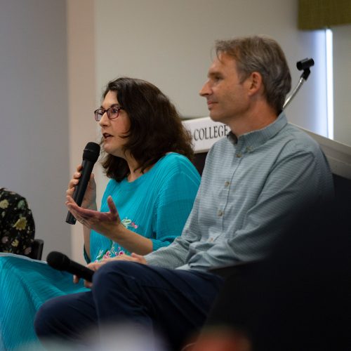 Four faculty seated in a row, one speaking into microphone