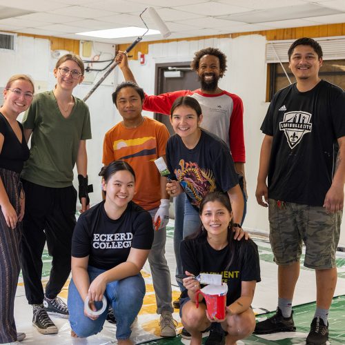 A group of student volunteers in a room with painting materials